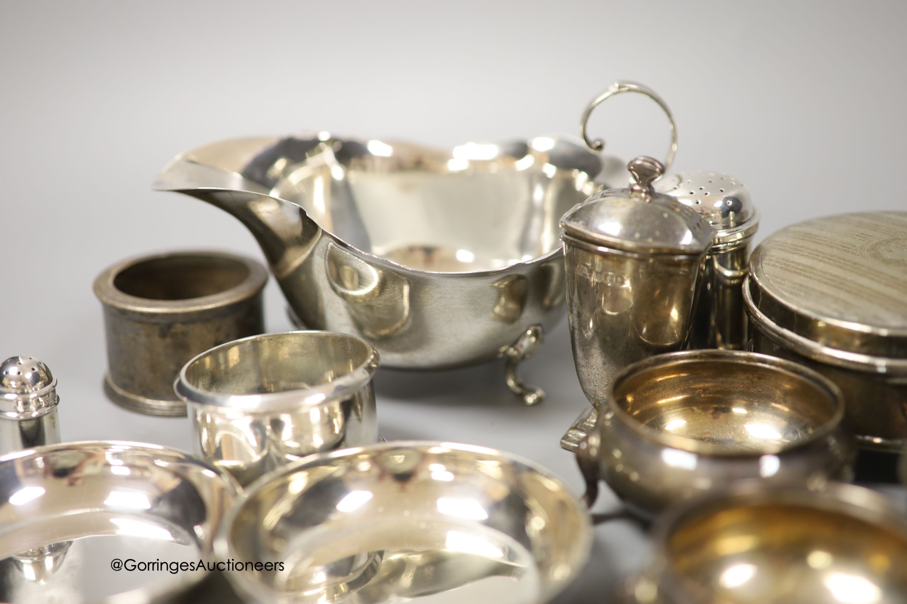 A group of minor silver including a George V trinket box, sauceboat, pair of soup spoons, pair of napkin rings, two bun salts, four small dishes, condiments etc. and three plated items.